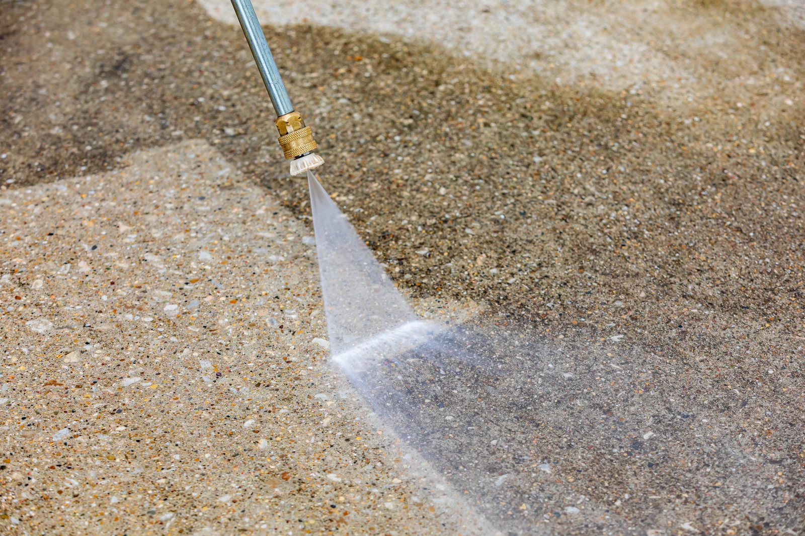 Close-up of pressure washing a concrete driveway
