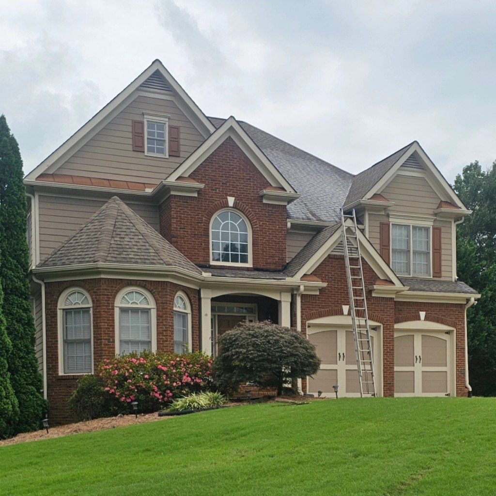 Two-story brick and siding home with ladder set up for exterior cleaning