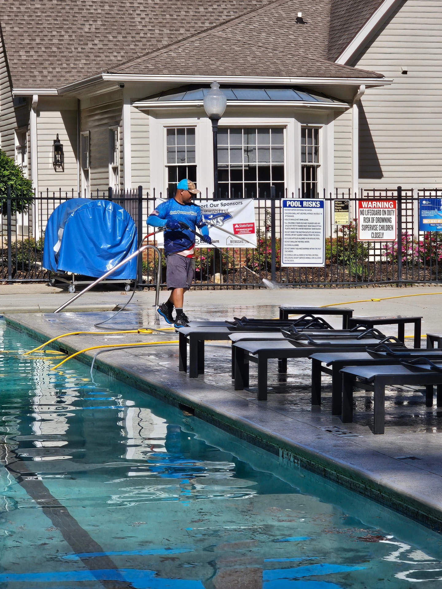 Technician pressure washing a concrete pool deck